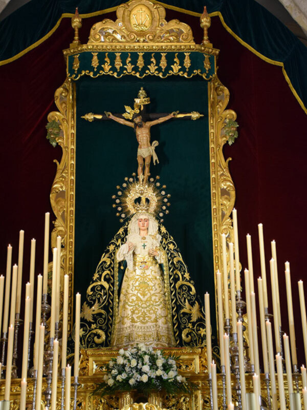 Altar con la Virgen de la Amargura y el Cristo crucificado, adornado con velas y flores.