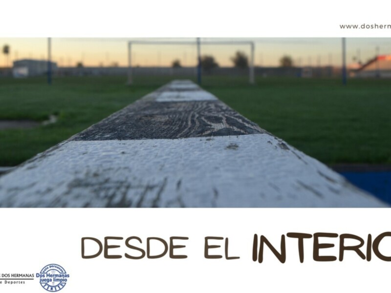 Un camino de piedra con letras grabadas, en un campo de fútbol al atardecer.